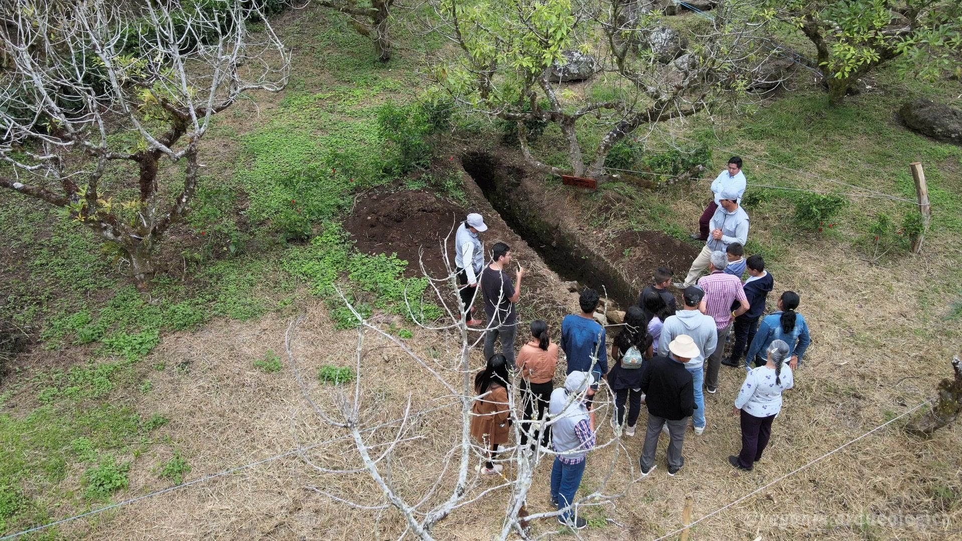 Group of visitors on a guided tour beside an excavation trench at Vegonia